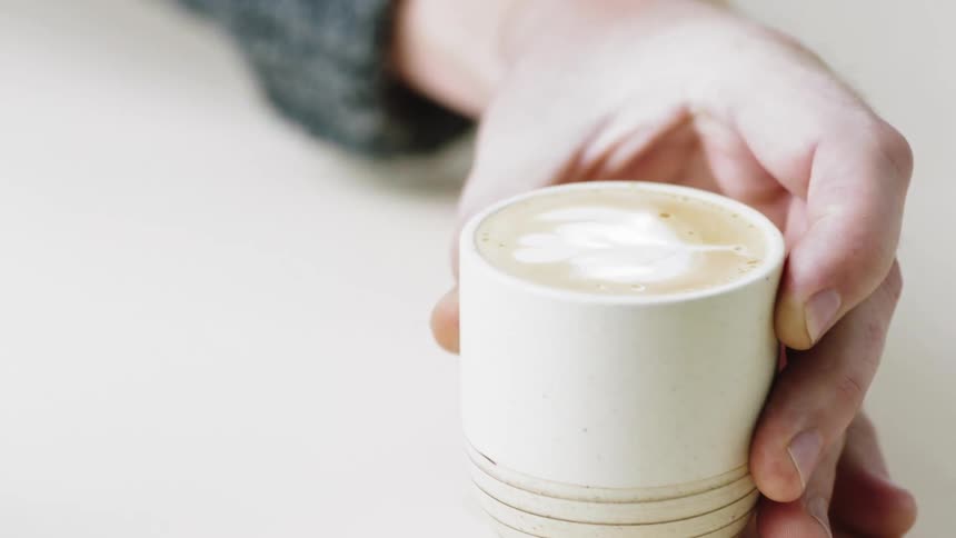 Milk is poured from a silver pitcher into a cup