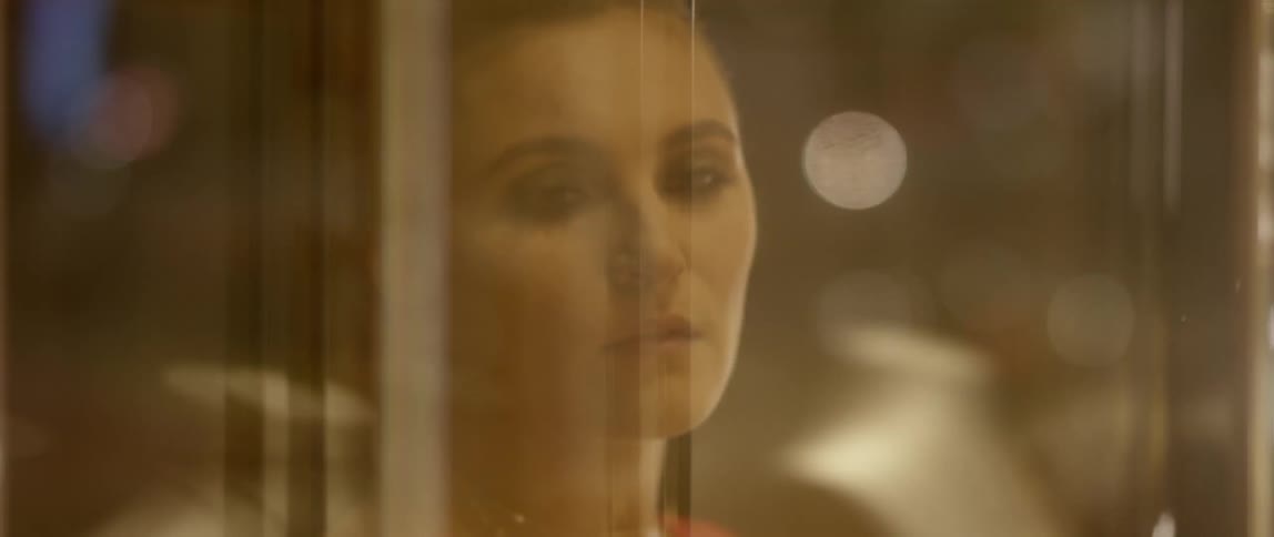 A woman looks out the window of her home and watches city traffic pass by
