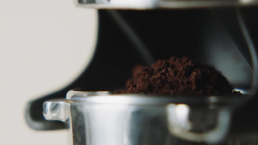 Ground coffee fills the stainless cup of an espresso machine