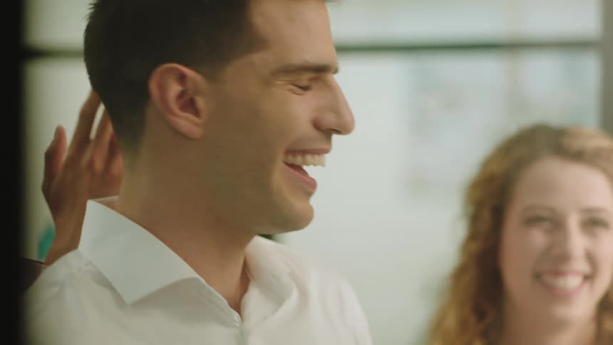 Man is being congratulated by a man and woman as they all smile and look happy