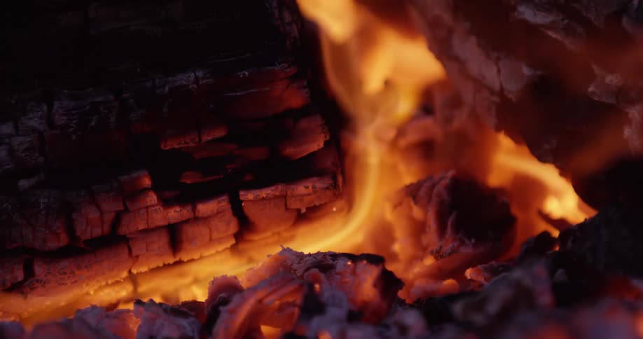 Fire burning charred wood as flames flicker in the breeze