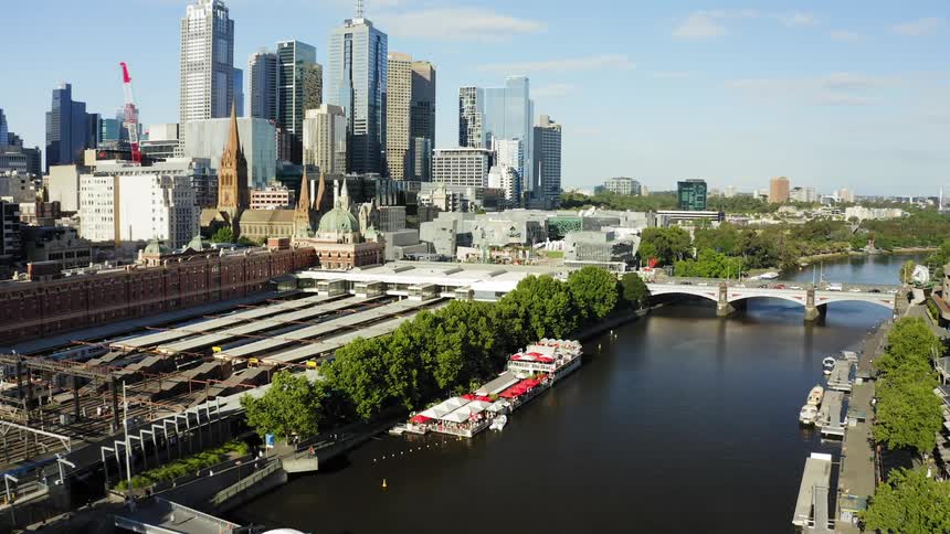 An arched bridge passes over a river and leads to downtown