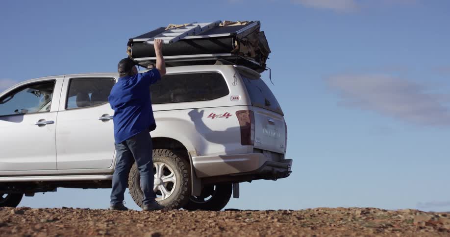 A man pulls a ladder from the top of his truck