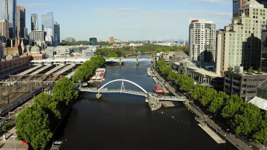 A river runs alongside train tracks in a city
