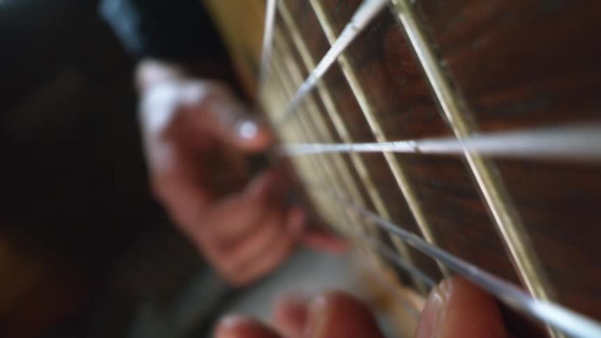 Person is playing a guitar and moving their fingers on the strings