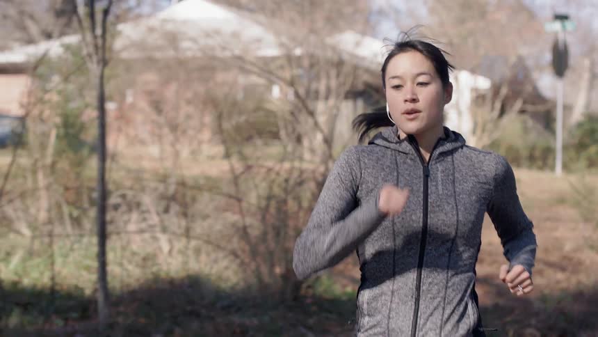 An asian woman jogging through a residential area