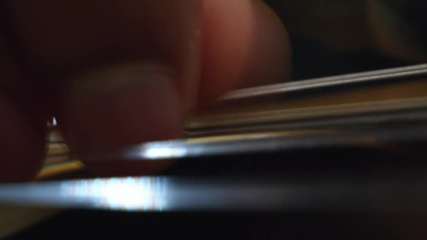 Guitarist is strumming the guitar strings with his thumb and finger