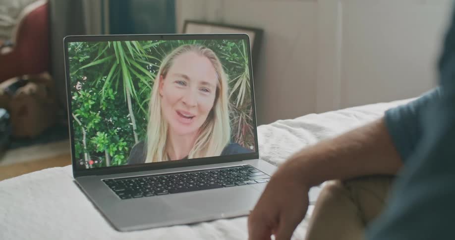 Man sitting on his bed video calling a woman on his laptop