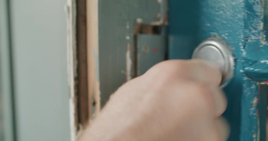 A hand holding a key and unlocking a blue door