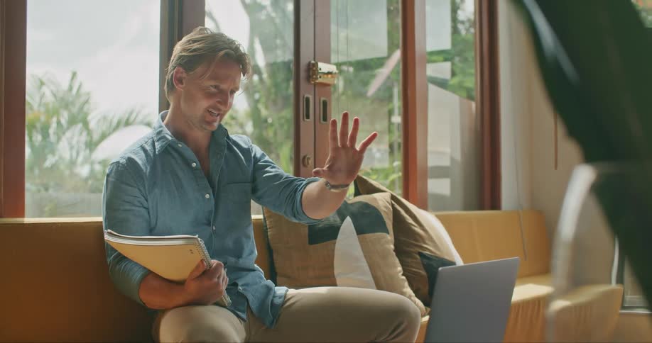 A man waves towards his laptop then closes it