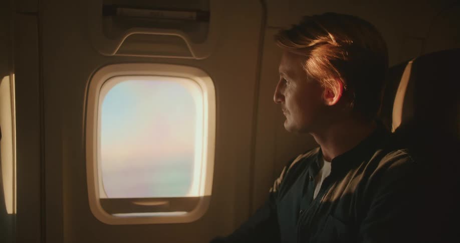 A man staring out the window of a plane