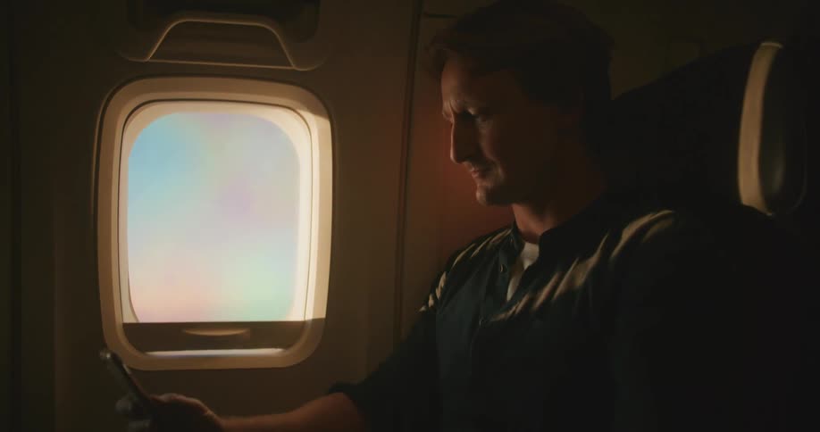 A man uses a cell phone on the plane