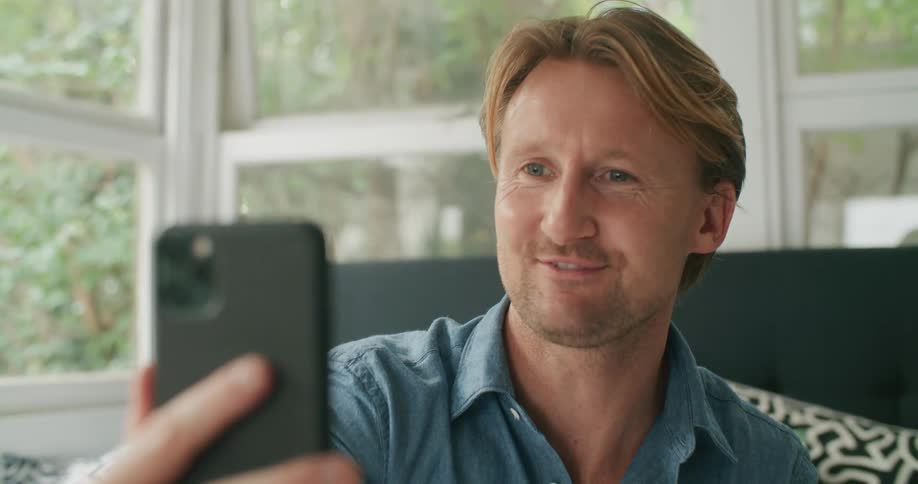White man talking and laughing while video calling someone on his cellphone
