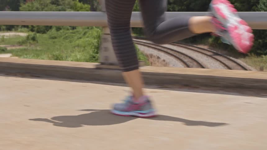 A woman is jogging on an overpass