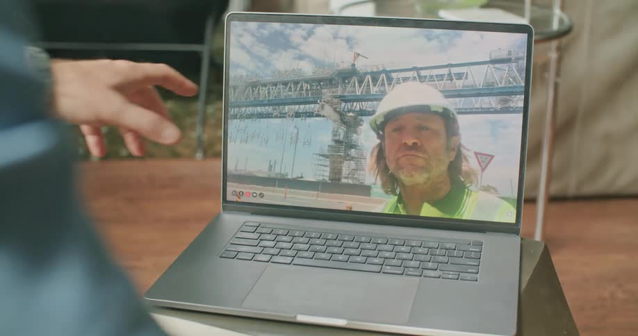 Man video calling a construction worker at his laptop