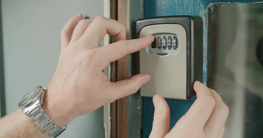 A man turns dials on a lock and opens a box and removes a key