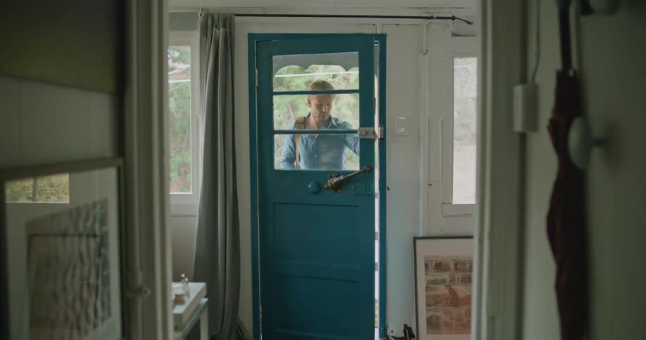 A man unlocks the front door and enters a house looking around as he walks