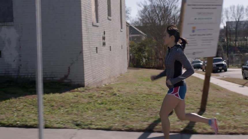 Brunette jogger running down a city street