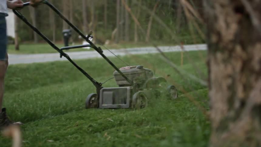 Person mowing a lawn while wearing shorts