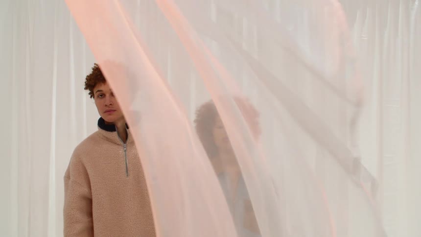 A man and woman standing behind a sheer billowing curtain