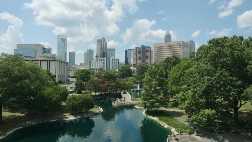 A river runs through a picturesque park filled with trees that connects to downtown
