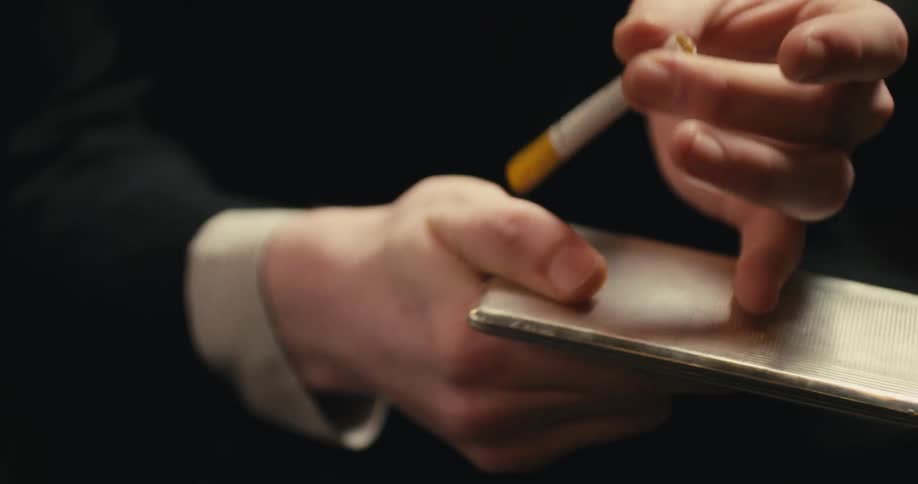 A person removing a cigarette from a silver metal case