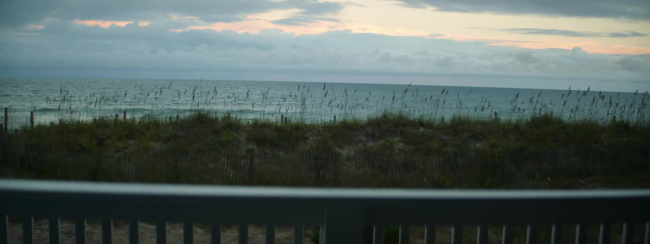 Small hill in front of sea seen from behind railings