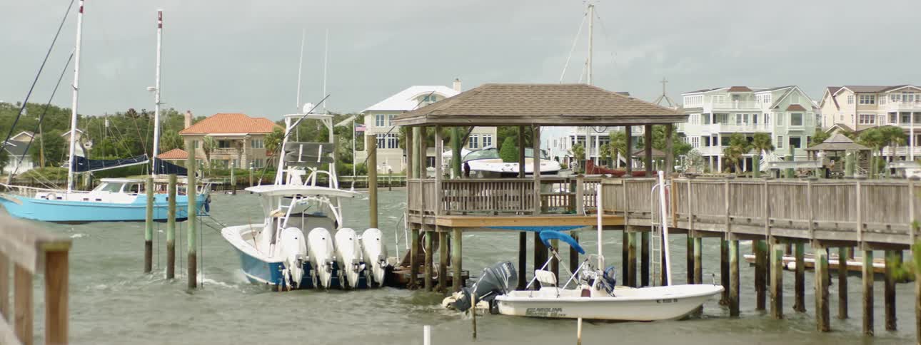 A harbor with boats with houses trees the sky and clouds in the background