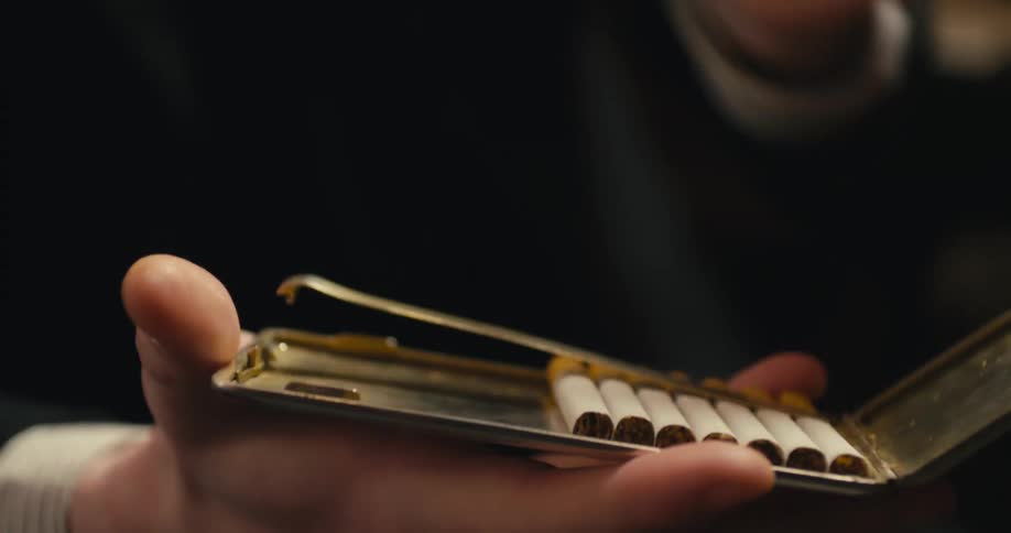 Person opens cigarette case to take cigarette then close case