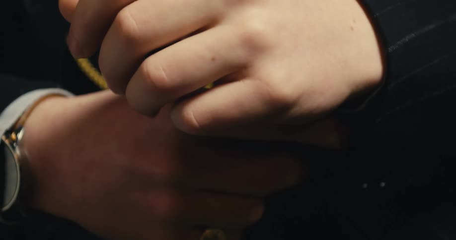 Man wearing suit jacket and adjusts his cuff links