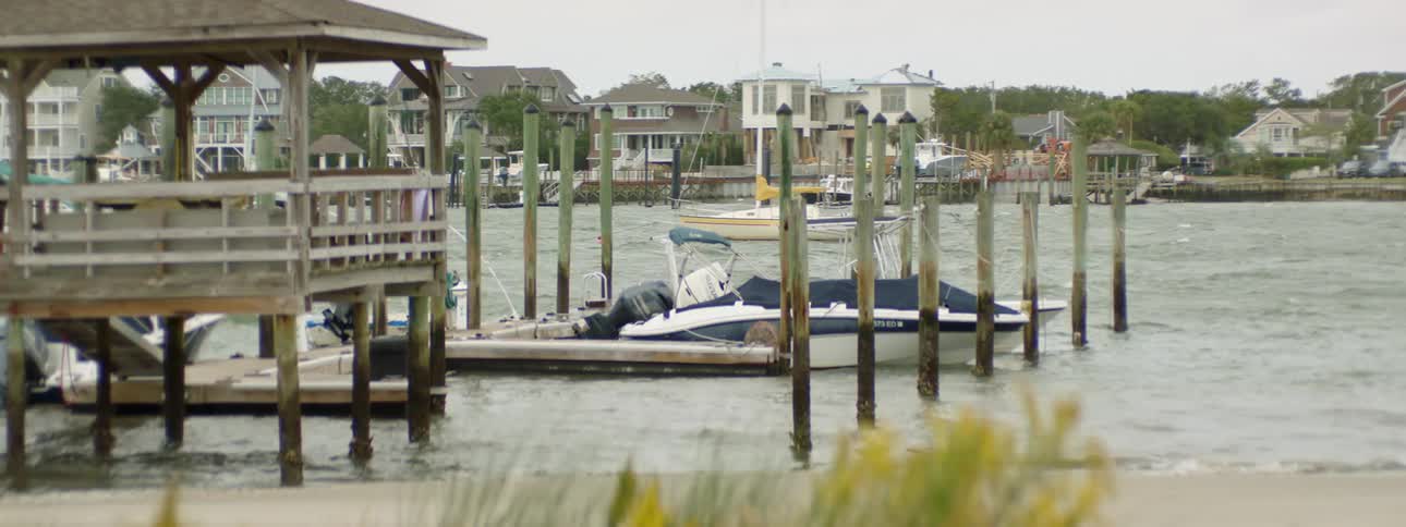 Several small boats bob in the water on a windy day at a coastal dock