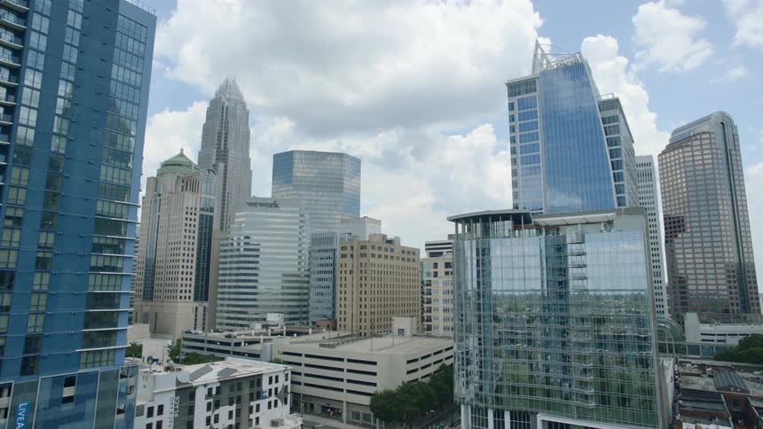 The surrounding buildings and sky are reflected on the window facades of city skyscrapers