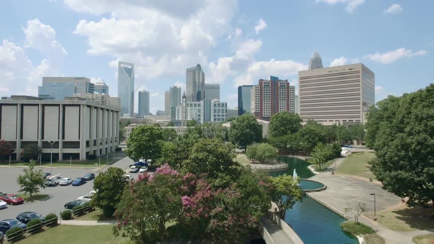 A river winds through a beautified public park and leads to a downtown city