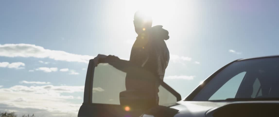 A man wearing sunglasses exits the passenger side of a sports car before closing the door behind himself