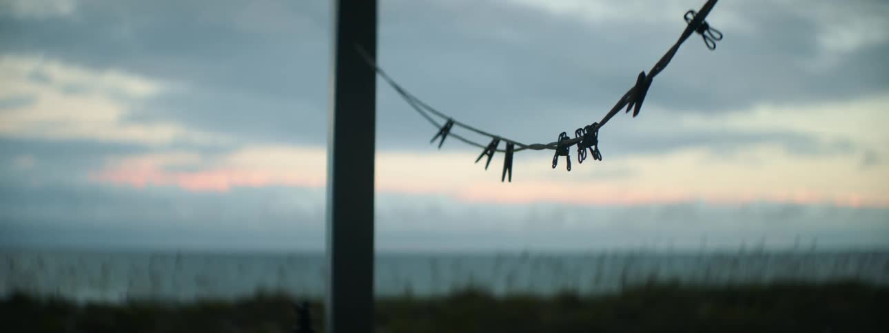 Garden washing line with clothes pin swaying in the wind against the beach at dusk