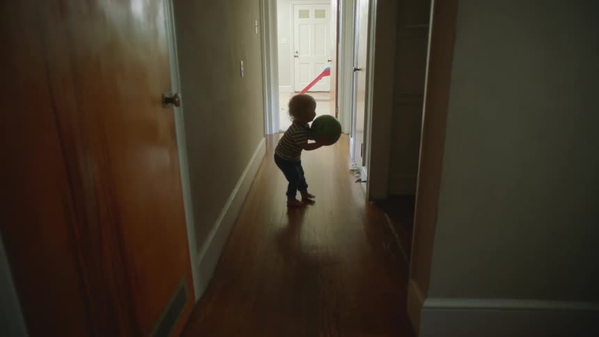 Child toddles into hallway picks up ball and leaves