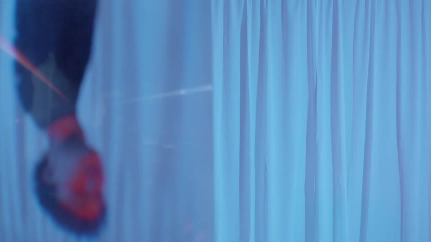 A teenage boy walking by a white curtain