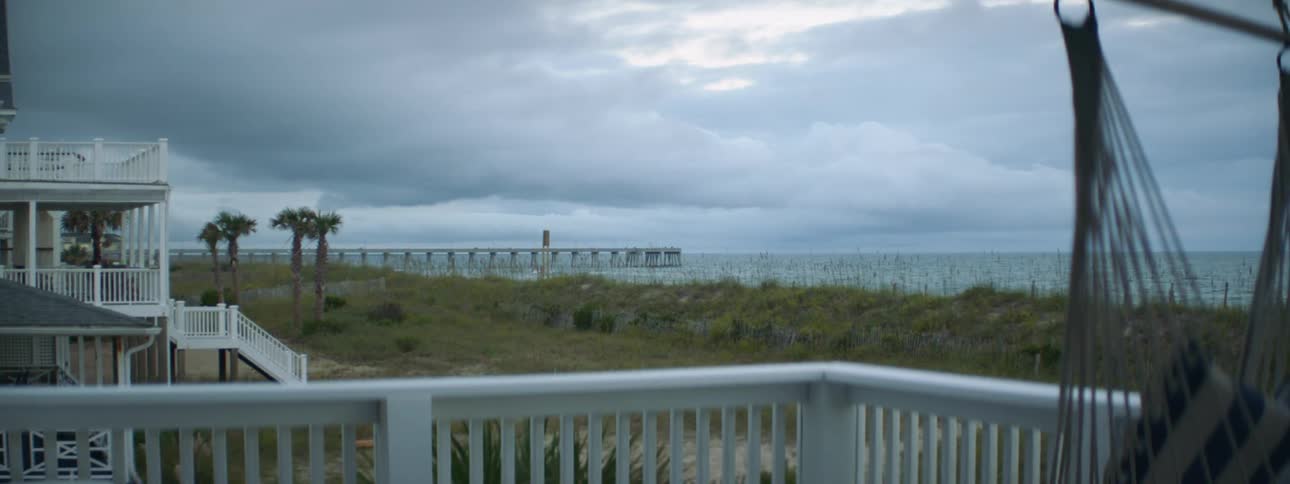 A rope swing sways on the porch of a home along the coast