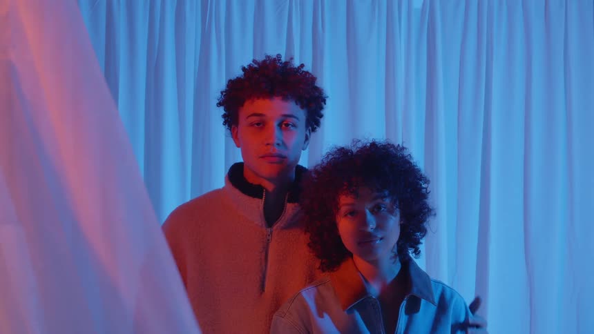 A man and woman are standing together next to a curtain