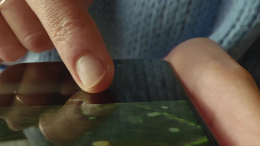 Macro probe lens close-up of a finger sliding a control on smartphone screen with a photo visible in the app. Filmed in soft daylight, capturing realistic tactile interaction, perfect for UX/UI, photography, and mobile technology projects.