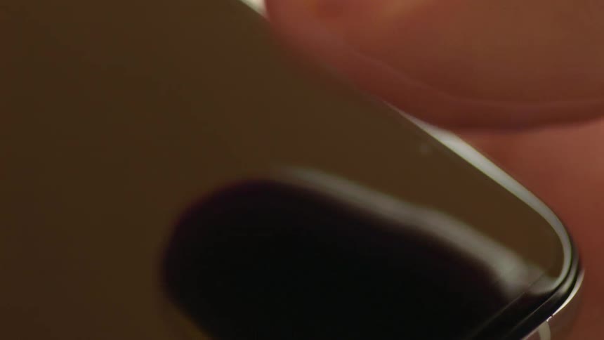 Cinematic macro close-up of a finger tapping on a black smartphone screen with blank display for screen replacement. Shot in warm natural light, perfect for VFX, app mockups, UX/UI design, and digital technology interaction projects.