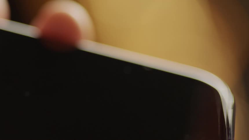 Cinematic macro close-up of a finger tapping on a black smartphone screen with empty display for screen replacement. Filmed with soft warm light, perfect for VFX, app mockups, UX/UI design, and digital interaction projects.