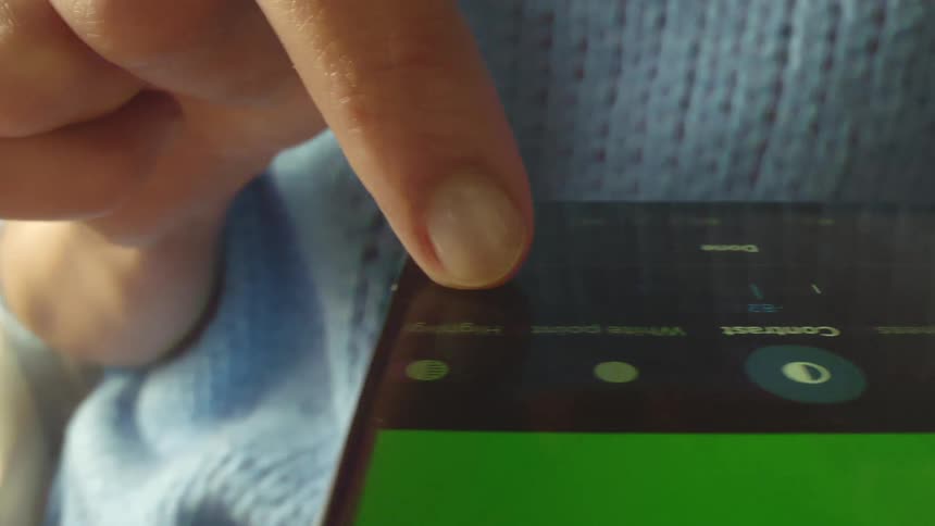 Cinematic probe lens close-up of finger swiping across smartphone screen to adjust a slider in photo app, with camera smoothly tracking the motion. Shot with probe snorkel lens, perfect for UX/UI, technology, and digital interaction projects.