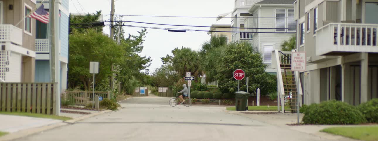 A man cycles down a neighborhood street