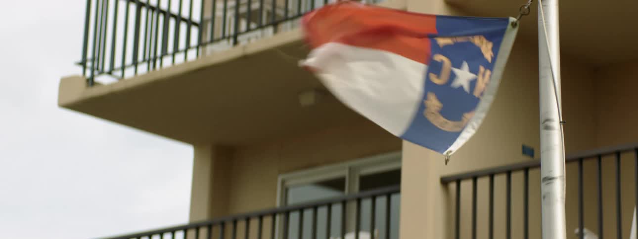 Flag flaps in wind near balconies bordered by black rail