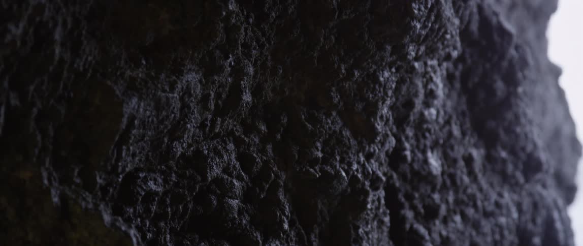 Panning down the face of a rock in shadow