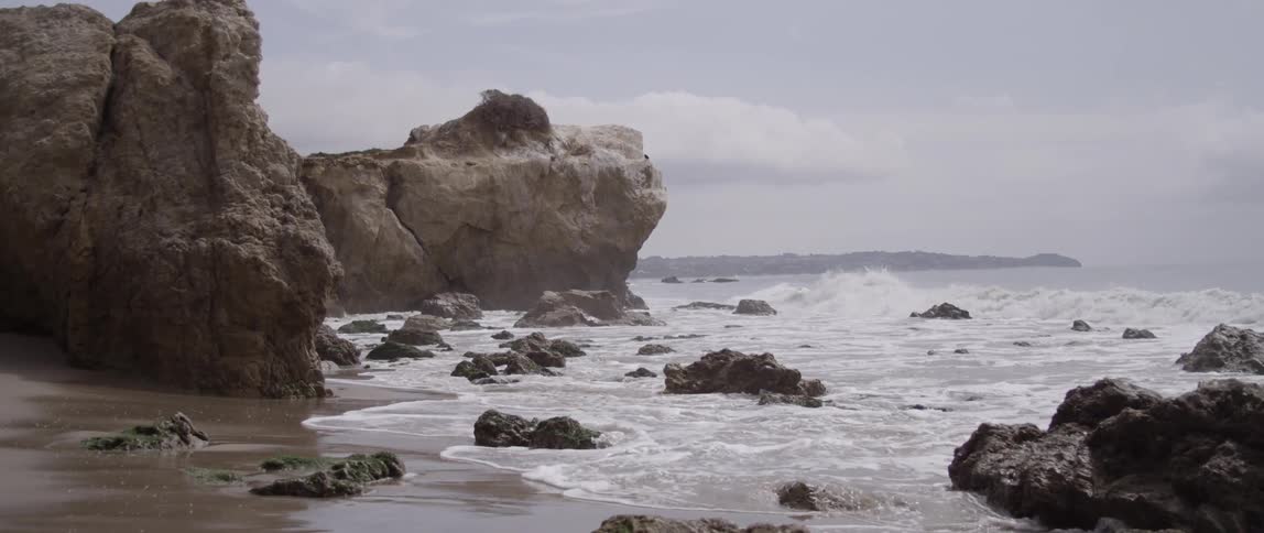 Waves are crashing against rocks on a beach