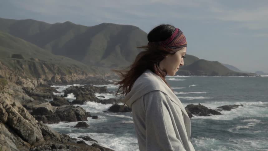 A woman in a gray shirt looks out at water