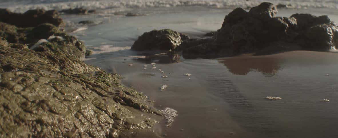 Water is crashing against rocks on the shore