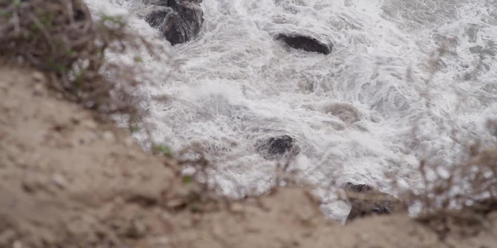 Waves slowly crash against rocks by the shore